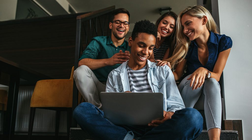 Person on computer being congratulated by friends.